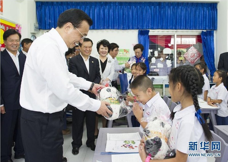 10月13日，正在泰國訪問的國務院總理李克強參觀具有110多年歷史的清邁崇華新生華立學校。這是李克強向三年級學生贈送大熊貓玩具。新華社記者 黃敬文 攝