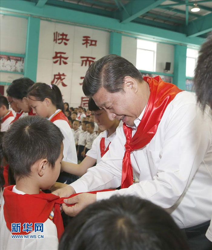 2014年5月30日上午，習近平來到北京市海澱區民族小學，參加慶?！傲弧眹H兒童節活動。這是習近平在少先隊入隊儀式上，為新少先隊員系上紅領巾。新華社記者 鞠鵬 攝